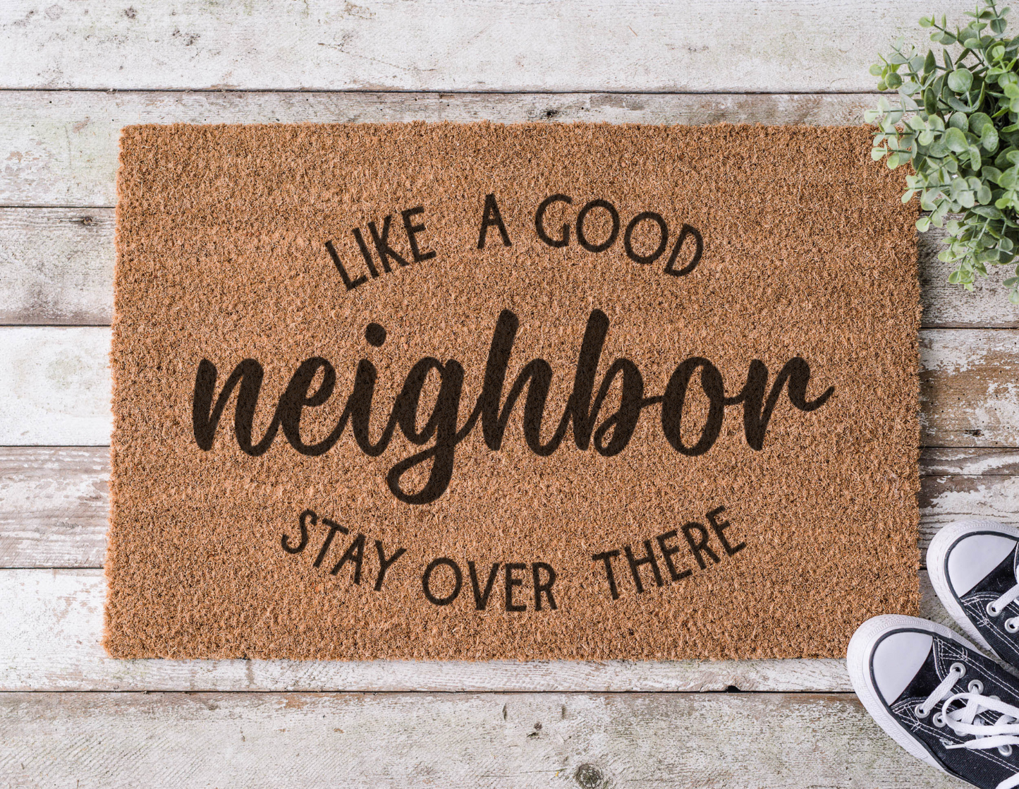 Coir doormat with the phrase ‘Like a Good Neighbor, Stay Over There,’ hand-painted in bold, humorous lettering