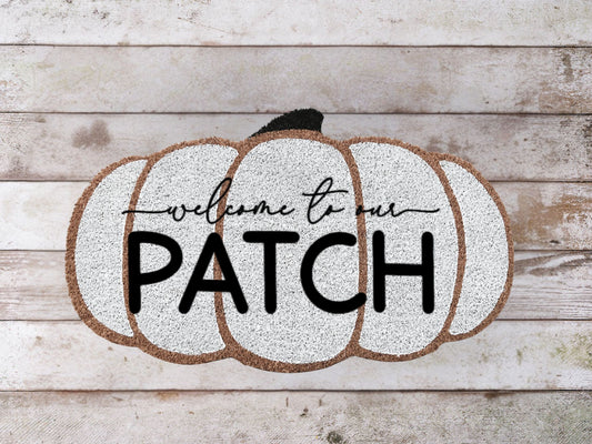 Coir doormat with the phrase 'Welcome to Our Patch' in playful lettering, decorated with small pumpkins and autumn leaves.