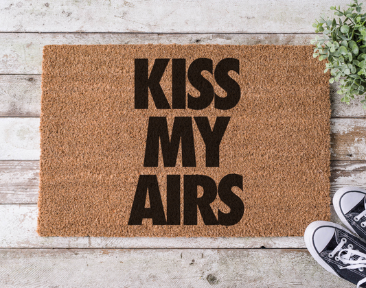 Coir doormat with the phrase ‘Kiss My Airs,’ hand-painted in bold, streetwear-inspired lettering with a nod to sneaker culture