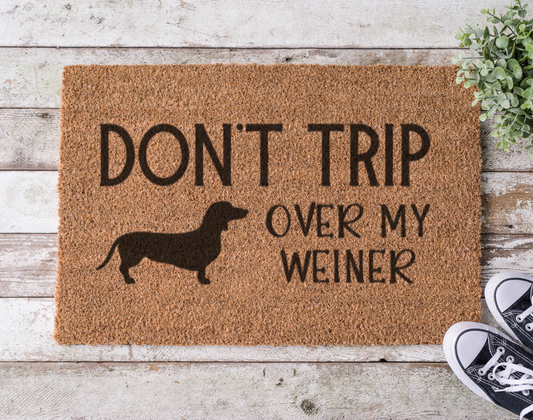 Coir doormat with the phrase ‘Don’t Trip Over My Wiener,’ hand-painted in playful lettering with a dachshund silhouette