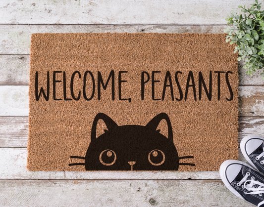 Coir doormat with the phrase ‘Welcome Peasants,’ hand-painted in playful black lettering with a cat-themed attitude