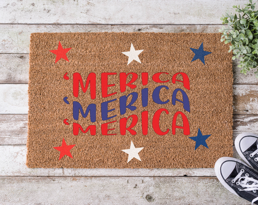 A rectangular doormat with a brown background and the word 'MERICA' written in bold, red and blue letters, surrounded by decorative stars in red and blue colors.